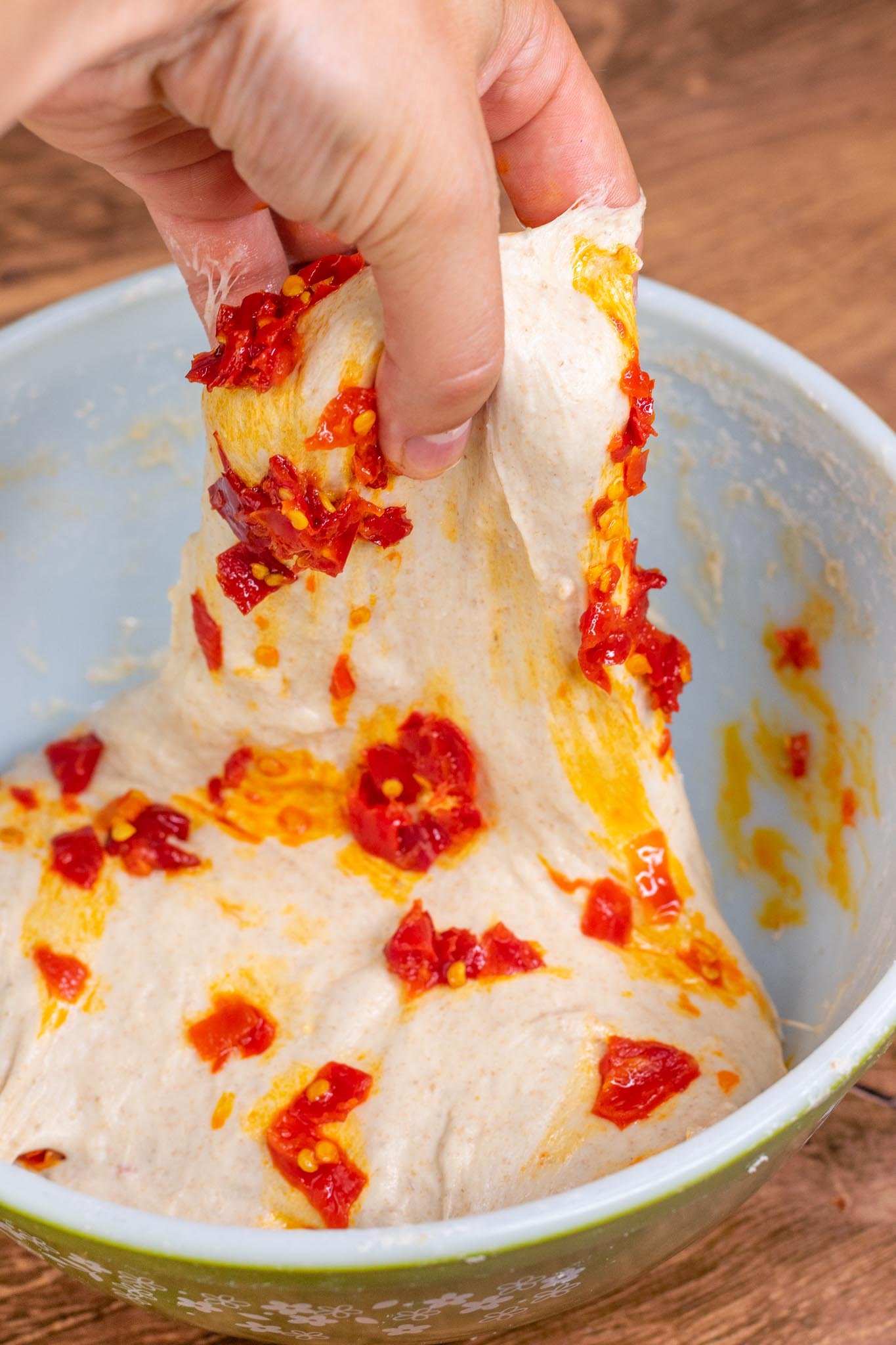 hand stretch and folding calabrian chilis into dough