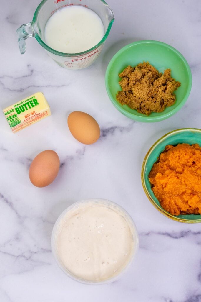 Wet ingredients needed for Sourdough Pumpkin Waffles including pumpkin puree, brown sugar, eggs, butter, sourdough discard, and buttermilk