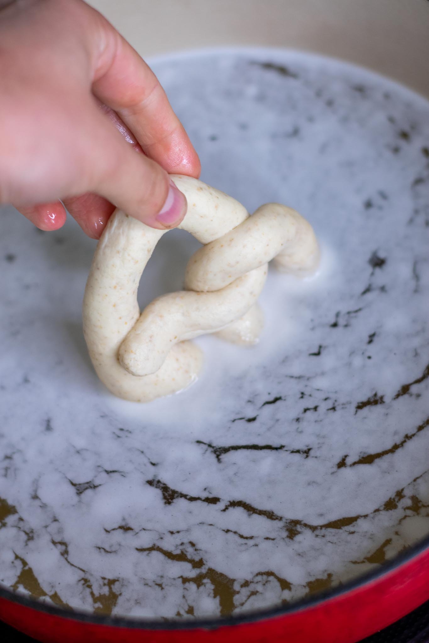 Dipping sourdough pretzel into baking soda bath