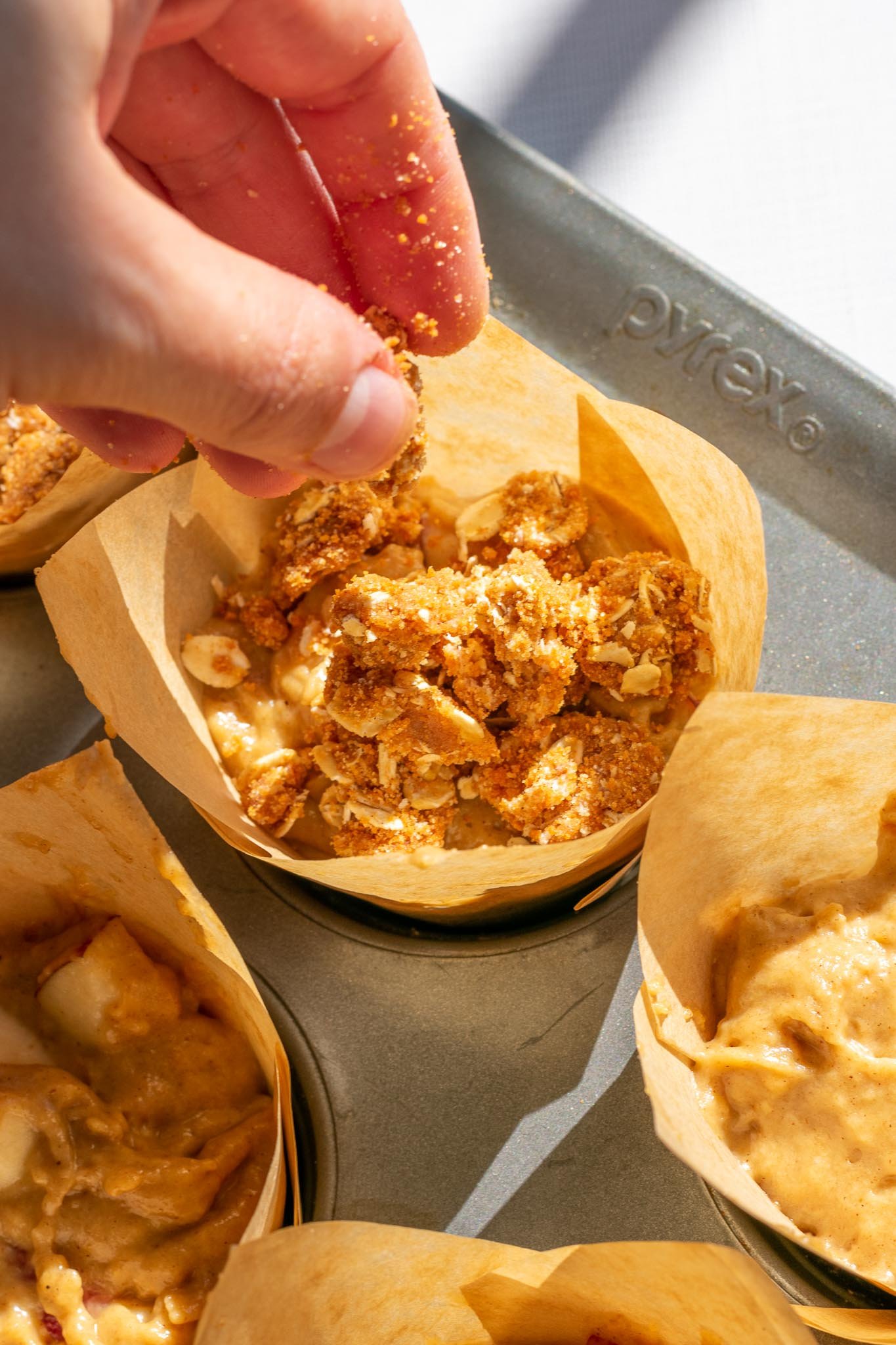 Sprinkling streusel onto sourdough apple butter muffins