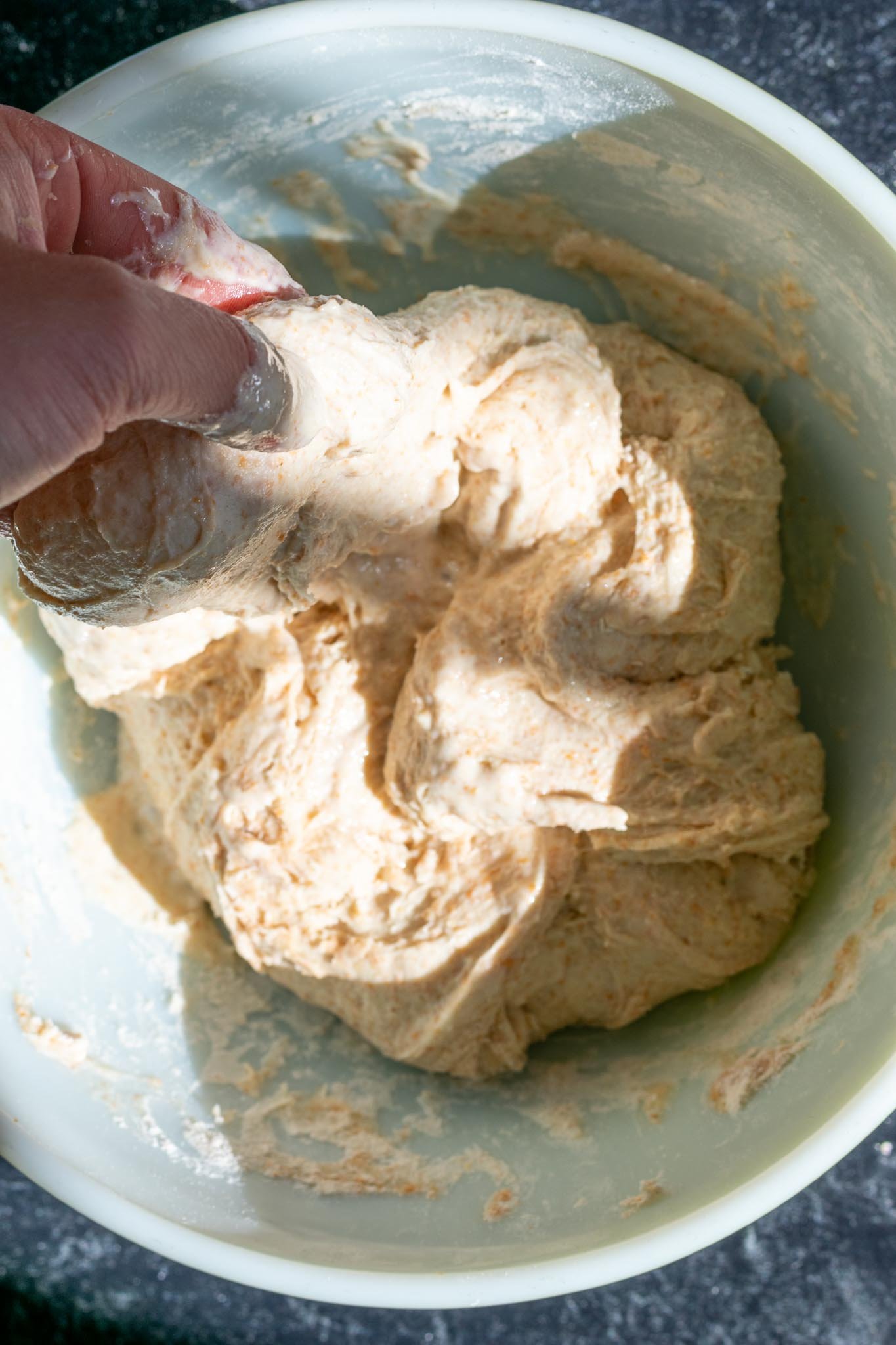 Mixing spelt sourdough bread in bowl with hand
