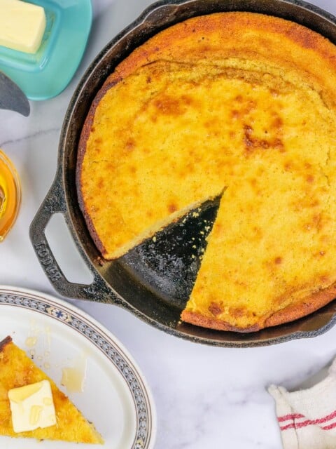 Sourdough Honey Cornbread in cast iron skillet with butter and honey