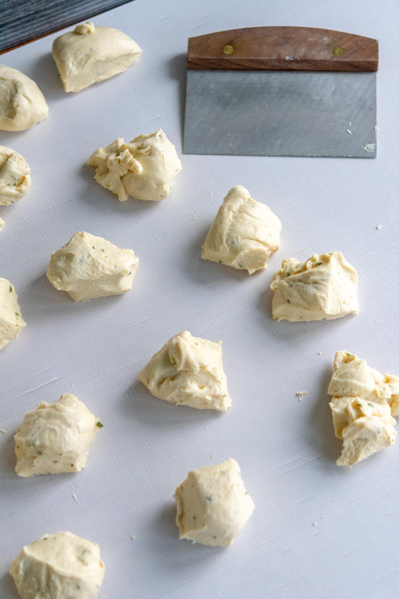 Many divided sourdough dinner roll doughs with a bench scraper