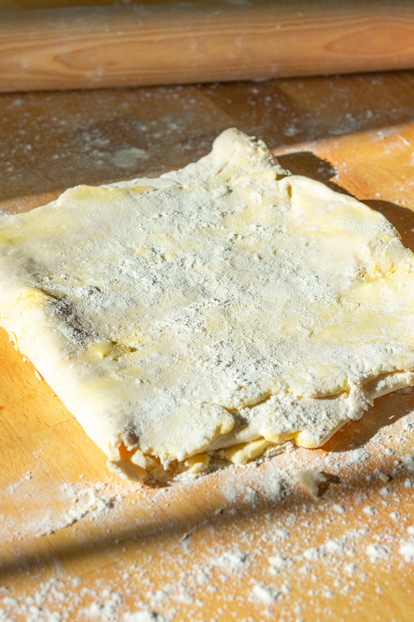 Folded Sourdough pie crust dough after lamination in a letter pocket