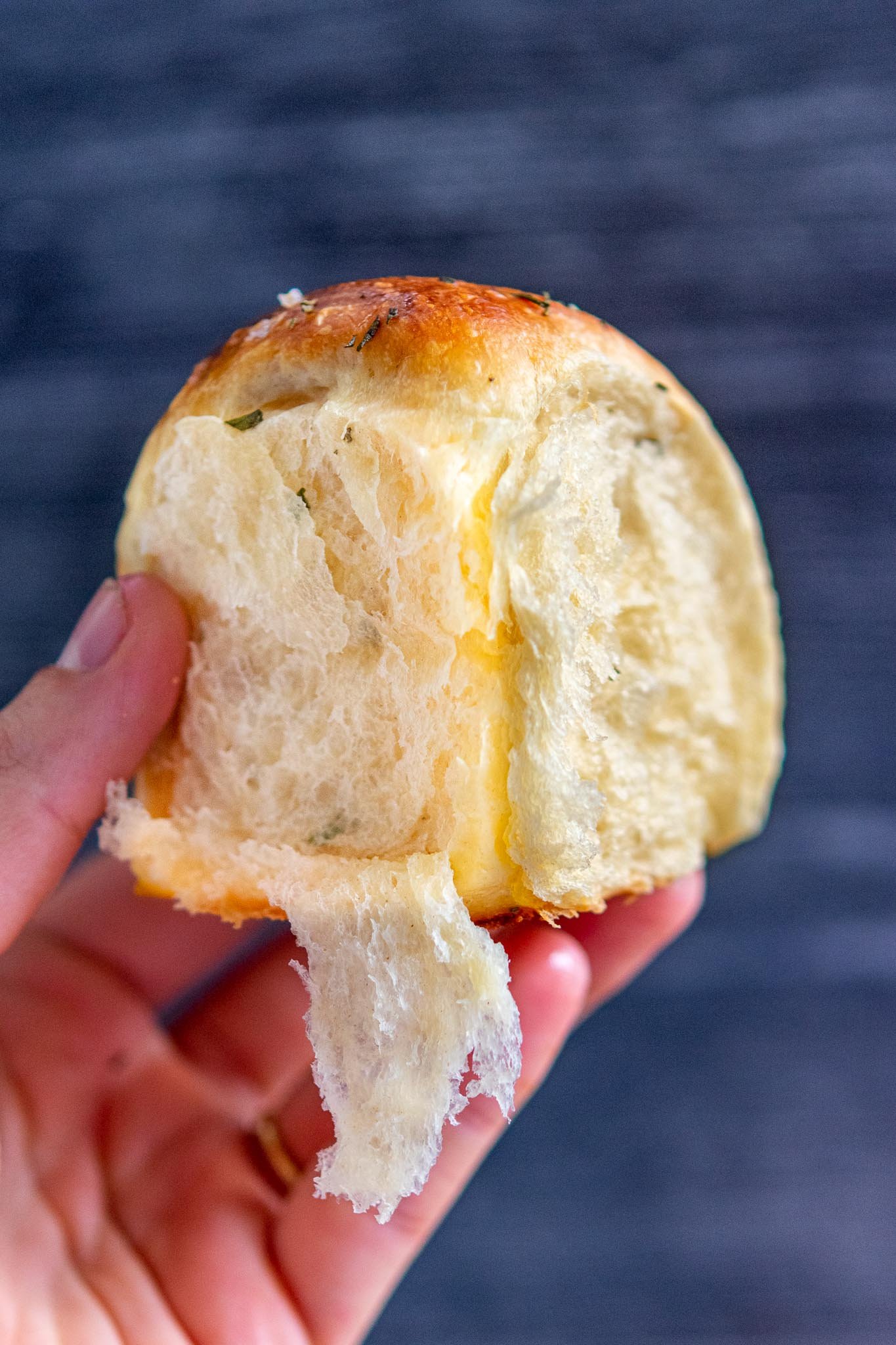 Hand holding a pull-apart Sourdough Dinner Roll with rosemary