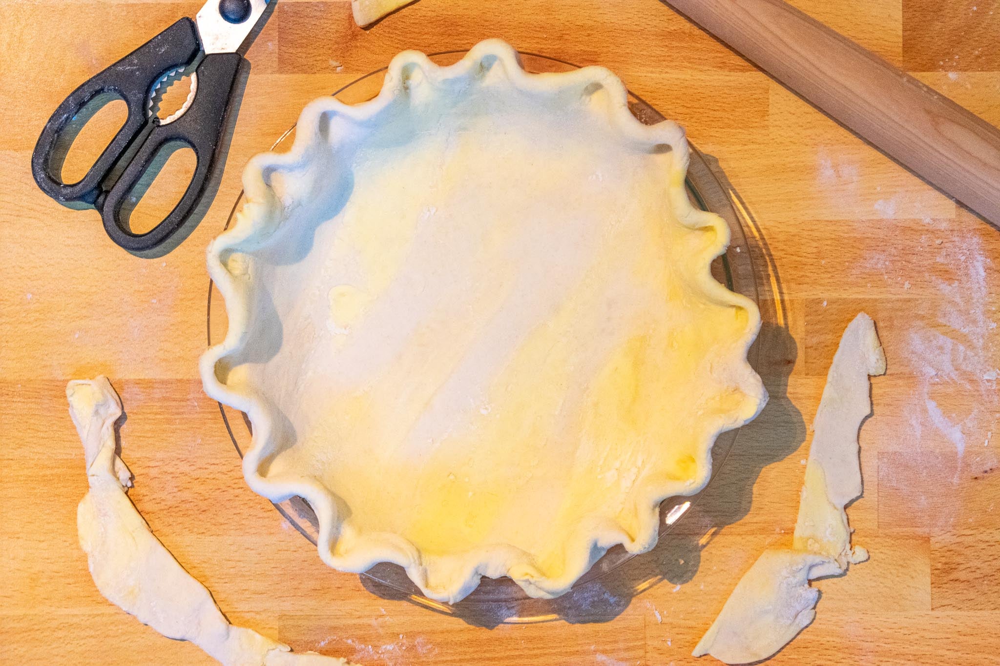 Sourdough Pie Crust rolled out and crimped in a pie plate with scissors and rolling pin