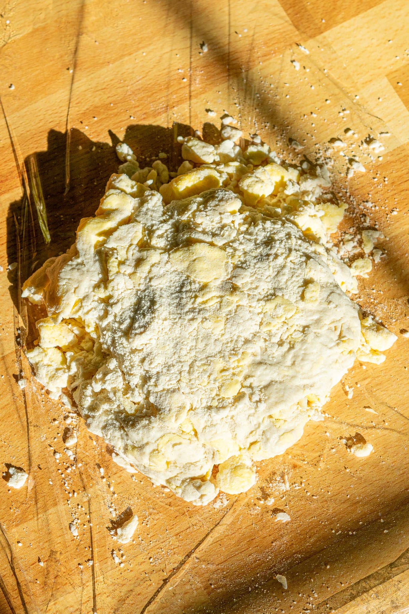 Sourdough pie crust dough with floury bits on plastic wrap