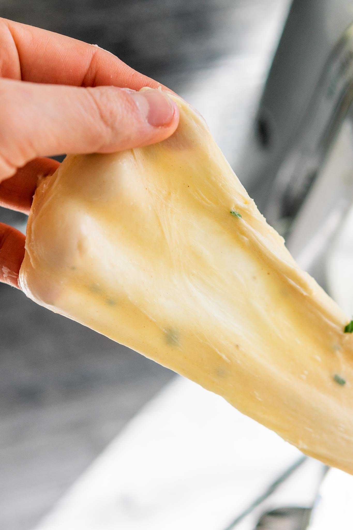 Hand pulling dough to pass the windowpane test
