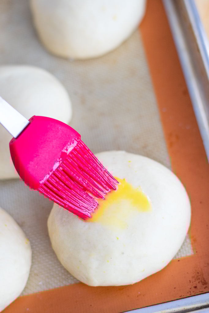 Brushing an egg wash on a sourdough maritozzo before baking