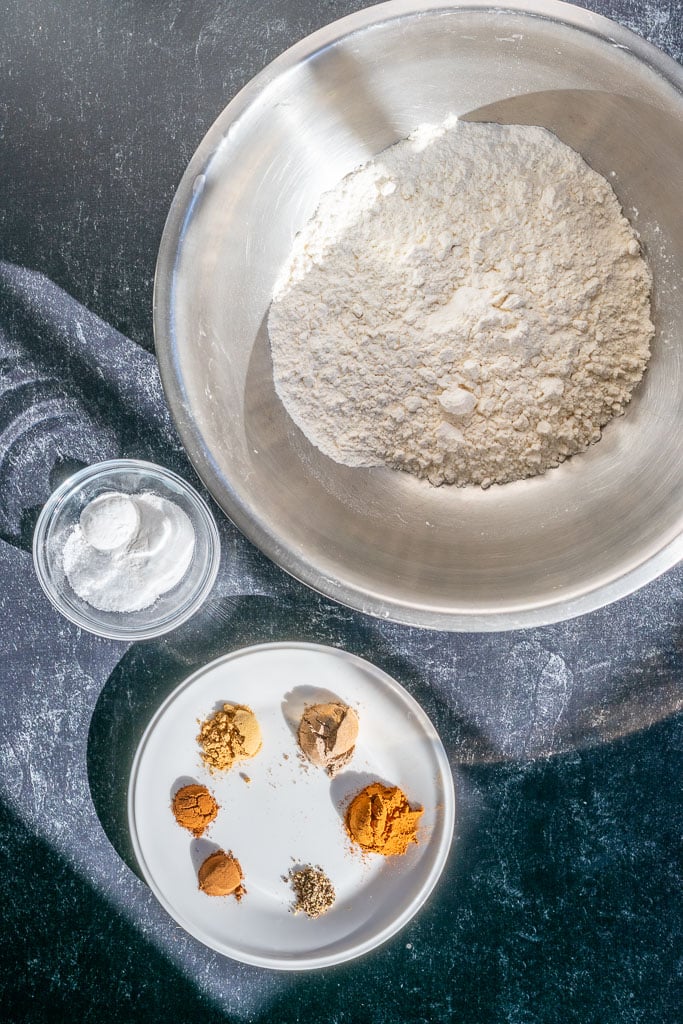Dry ingredients needed for sourdough banana bread including flour, salt, baking powder, baking soda, and masala chai spices