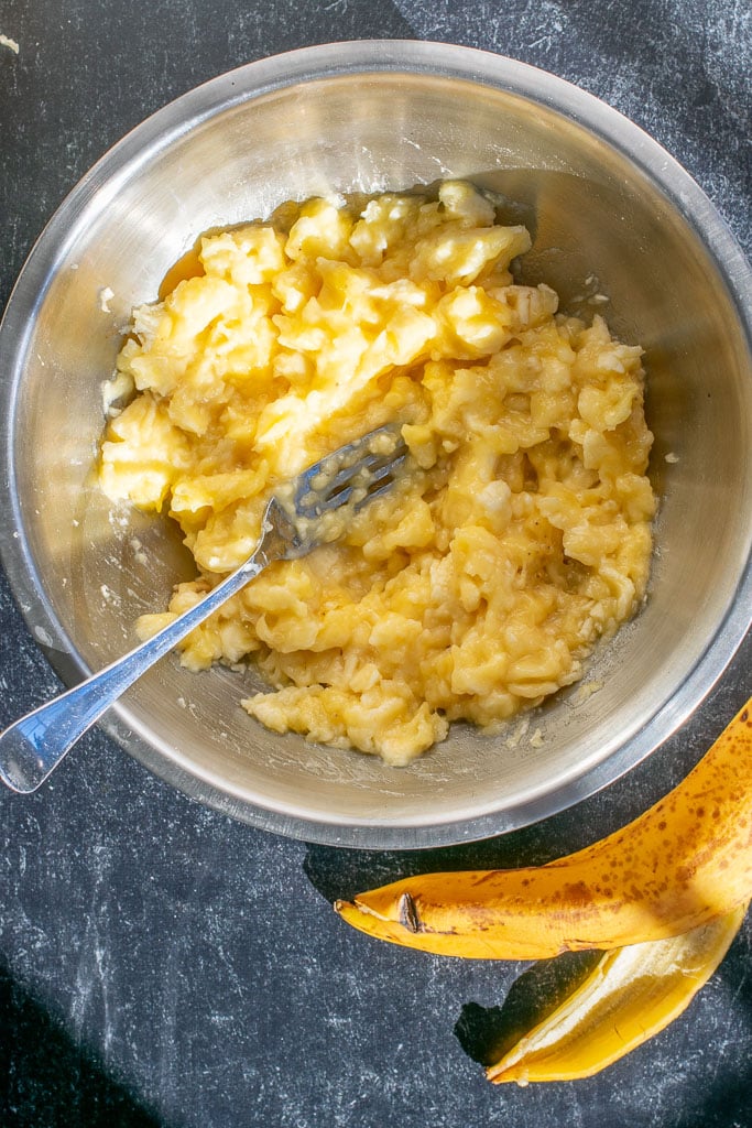 Mashing ripe bananas in bowl with a fork