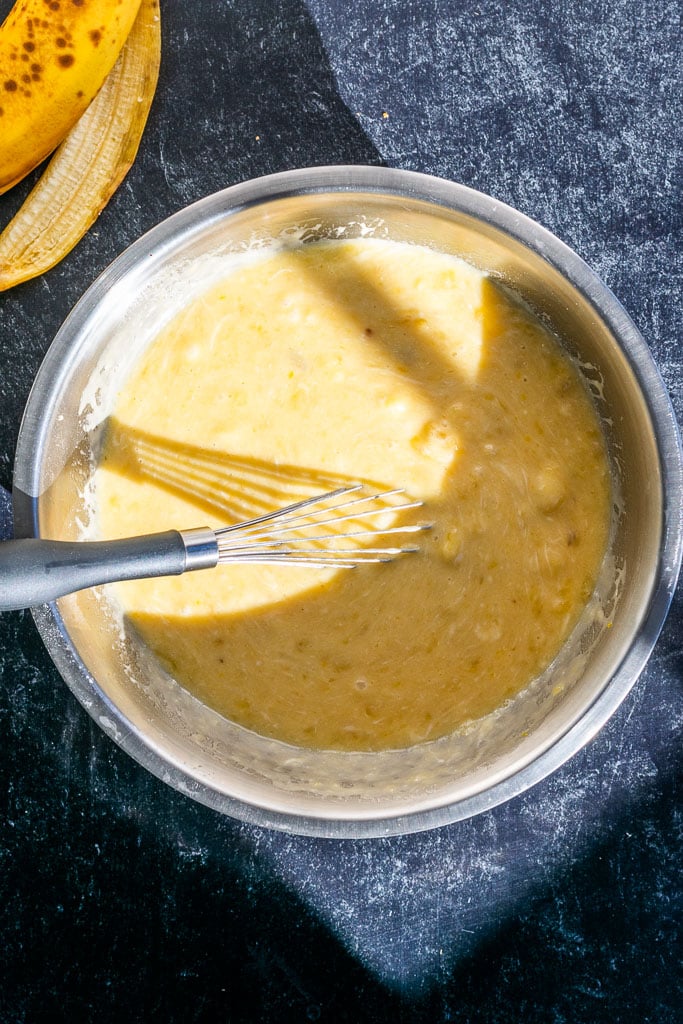 Mixed wet ingredients for sourdough banana bread in bowl with some lumps remaining