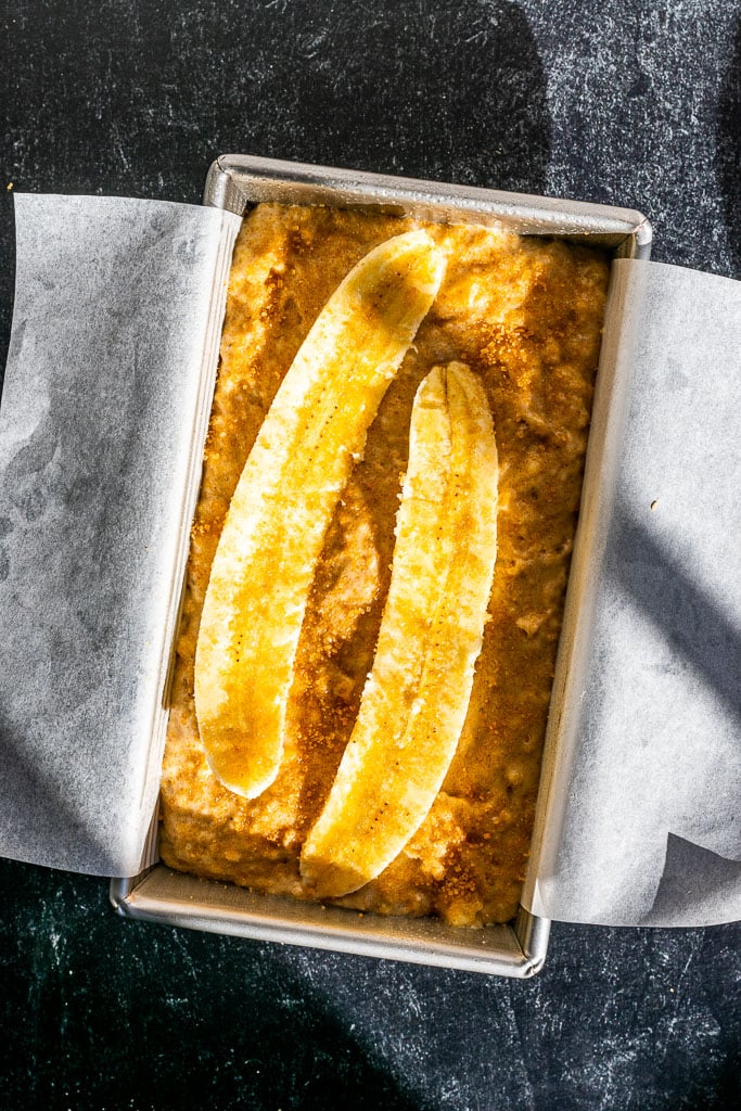 Sliced bananas and demerara sugar sprinkled on top of unbaked sourdough banana bread