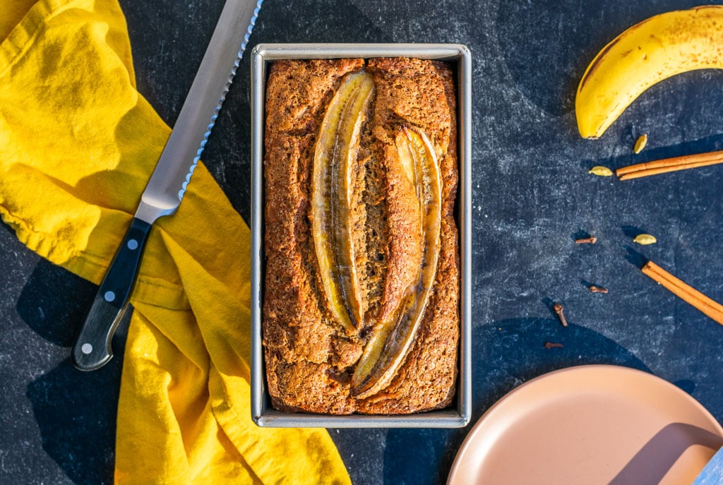 Sourdough banana bread in bread loaf pan with bread knife and chai spices