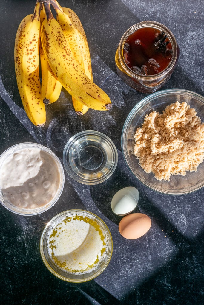 Wet ingredients needed for sourdough banana bread including bananas, light brown sugar, eggs, sourdough starter, butter, coconut oil, and vanilla extract