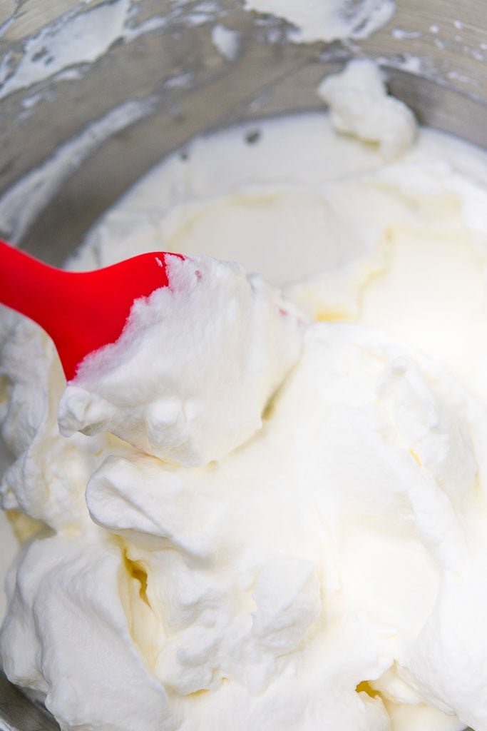 Mixed whipped cream with stiff peaks in a bowl with a spatula