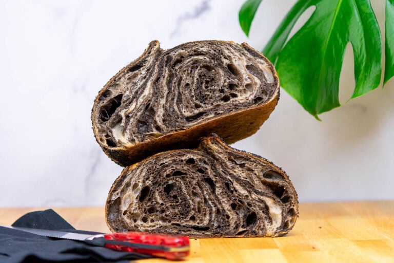 Black sesame sourdough bread sliced in half with a black and white swirl interior