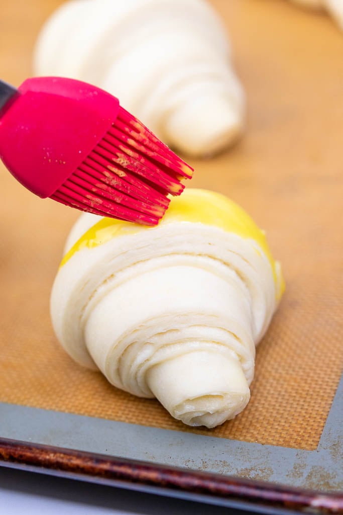 Brushing egg wash on a croissant
