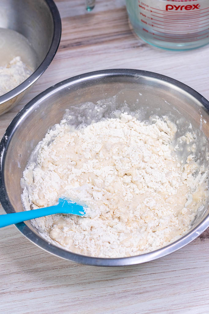 Spatula mixing flour and water in a mixing bowl for autolyse