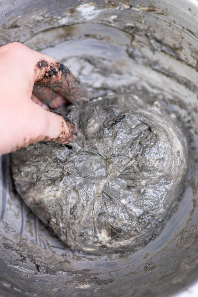 Hand mixing black sesame sourdough dough in mixing bowl