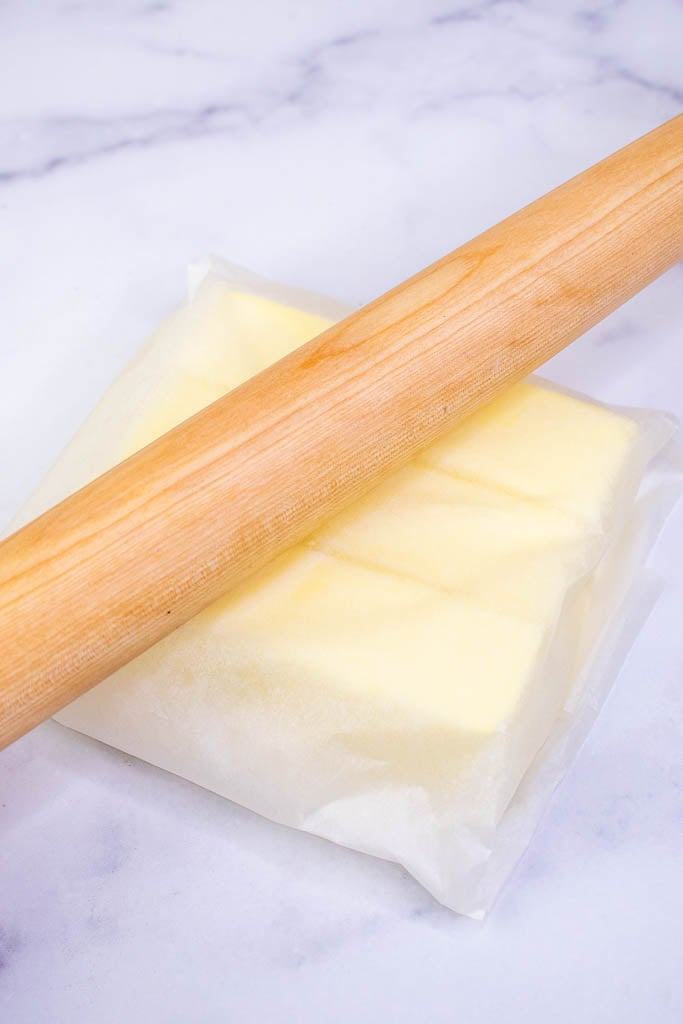 Rolling pin smashing butter in parchment paper