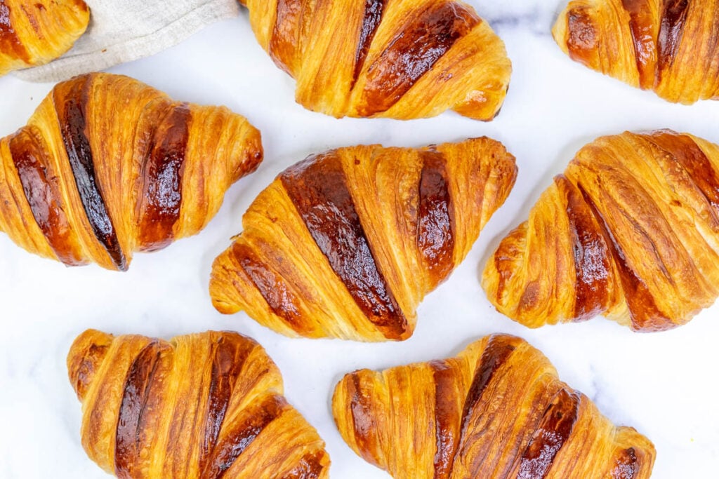 Multiple sourdough croissants on a marble surface