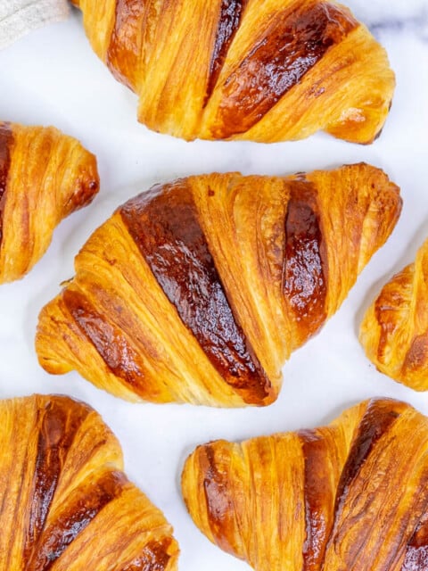 Multiple sourdough croissants on a marble surface