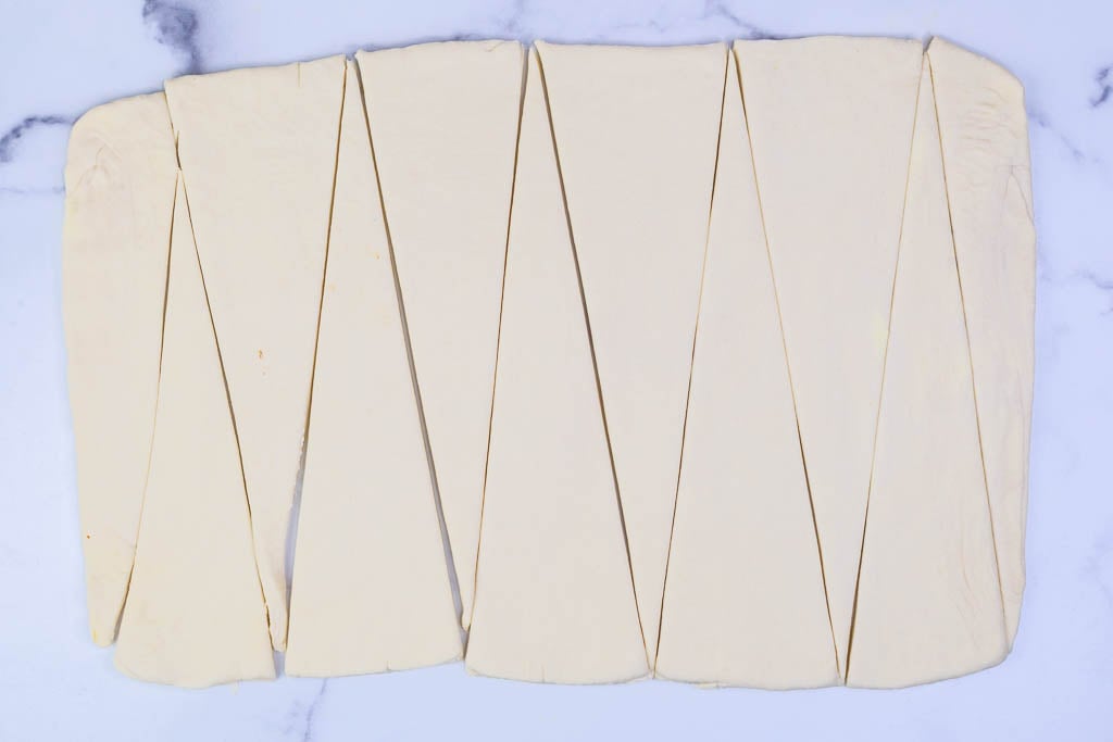Overhead of croissant triangles cut from dough