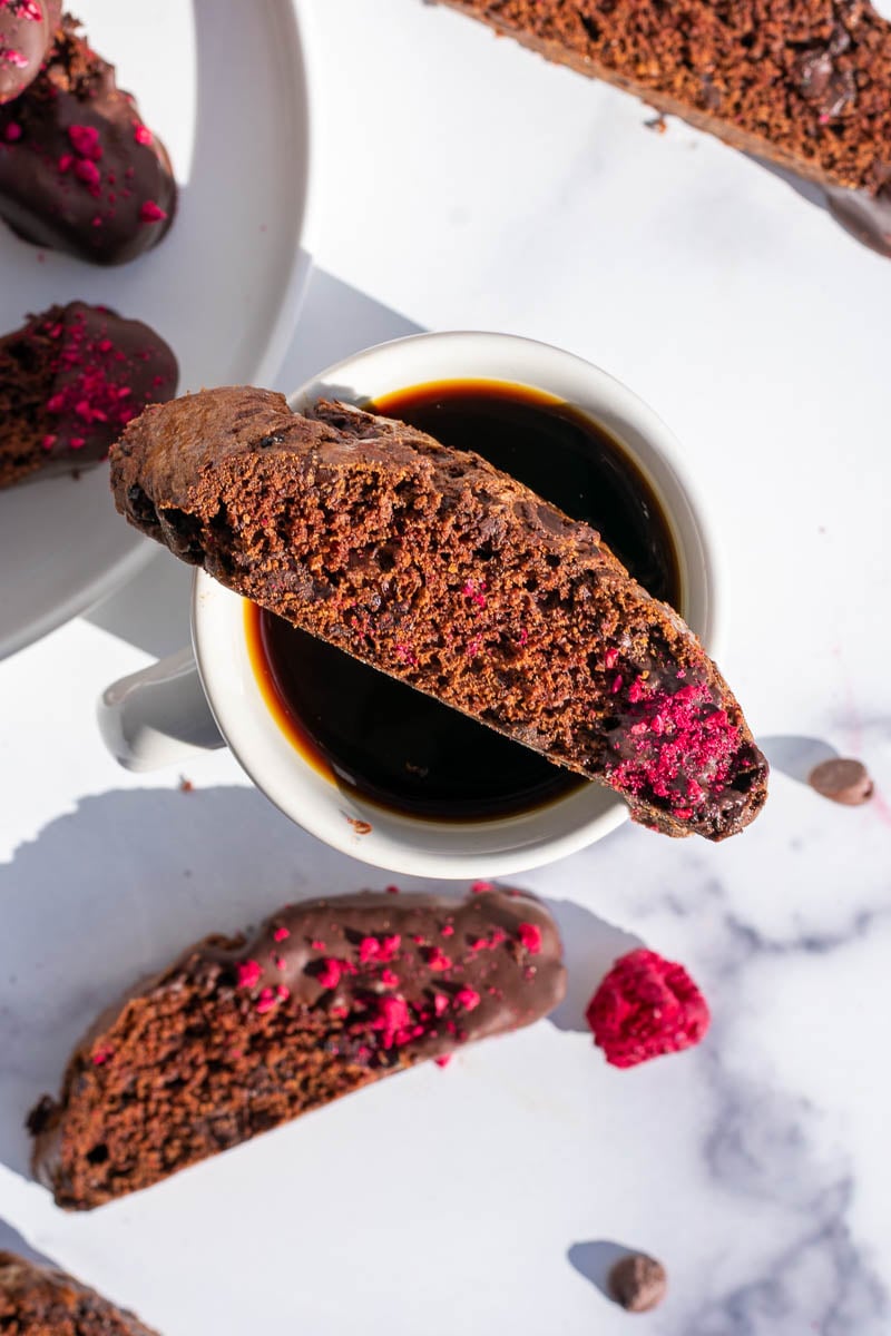 Chocolate raspberry sourdough biscotti laid on top of a coffee mug
