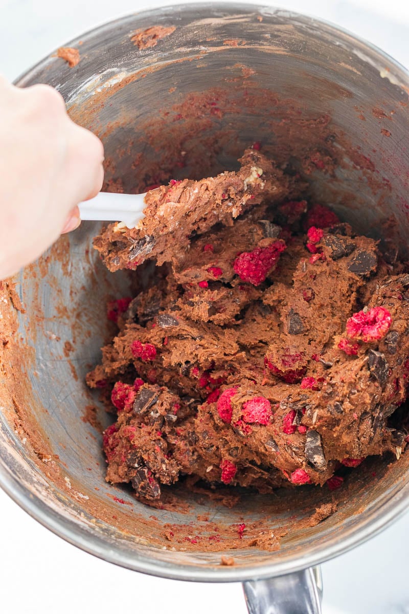 Folding chocolate and raspberries into biscotti dough with a spatula
