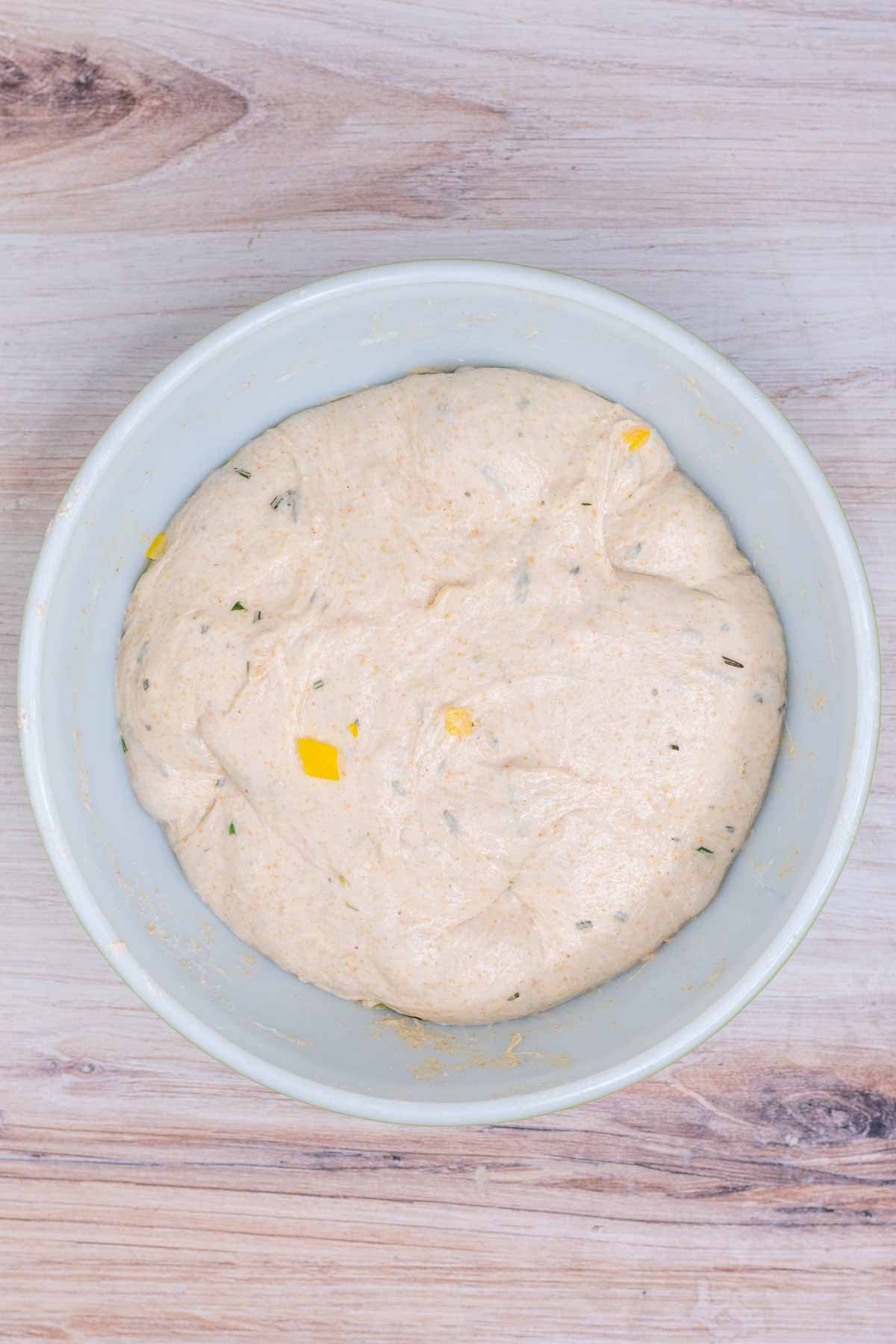 Dough with preserved lemons and rosemary doubled in size at the end of bulk fermentation in bowl