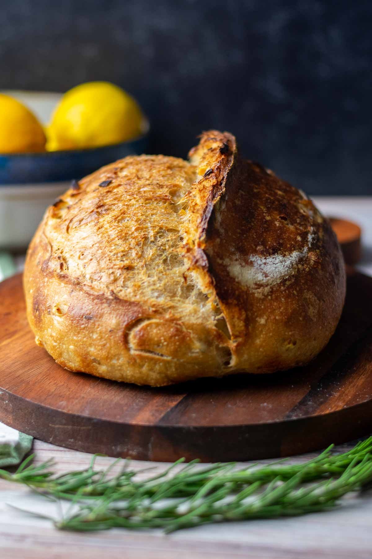 Loaf of preserved lemon and rosemary sourdough bread in morning light on a cutting board