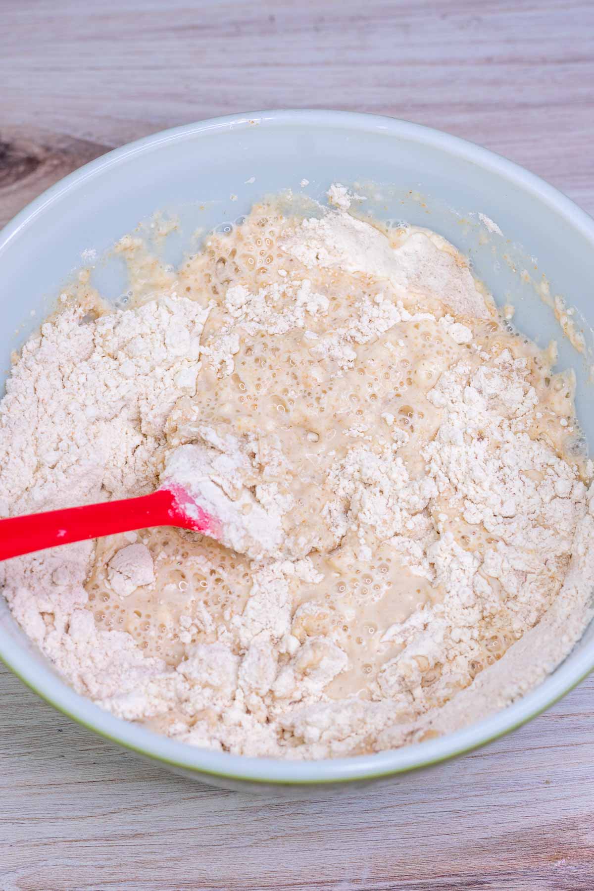 Mixing flours and water with a spatula in a bowl for autolyse