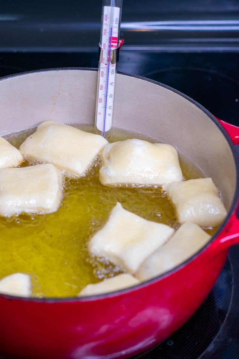 Sourdough beignets puffed up in pot of hot oil.
