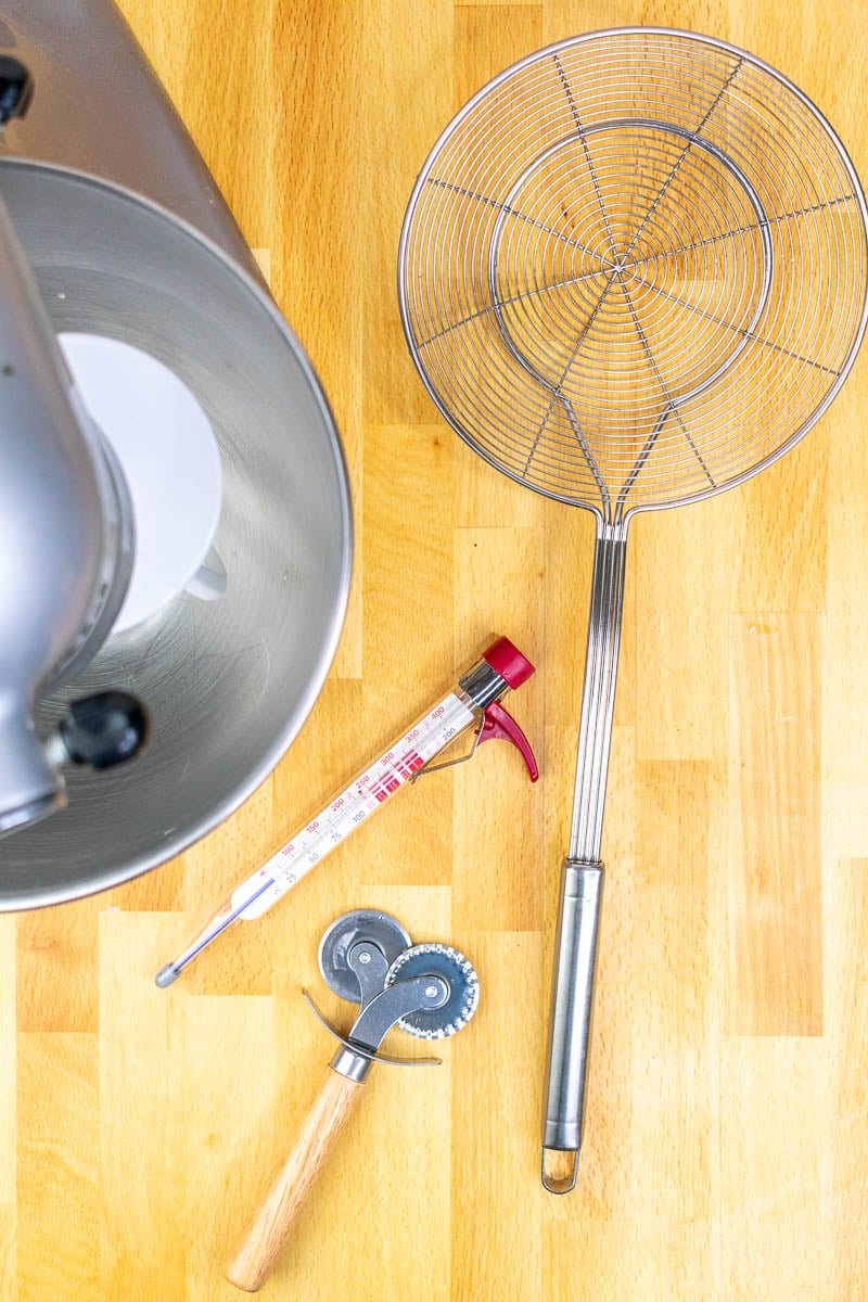 Tools needed for sourdough beignets including stand mixer, thermometer, pastry wheel, and spider strainer