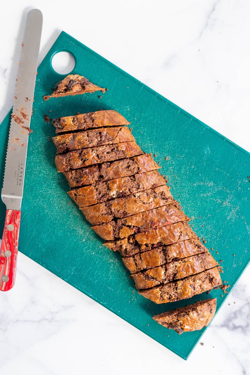 Sourdough biscotti sliced into pieces on a cutting board with a read knife