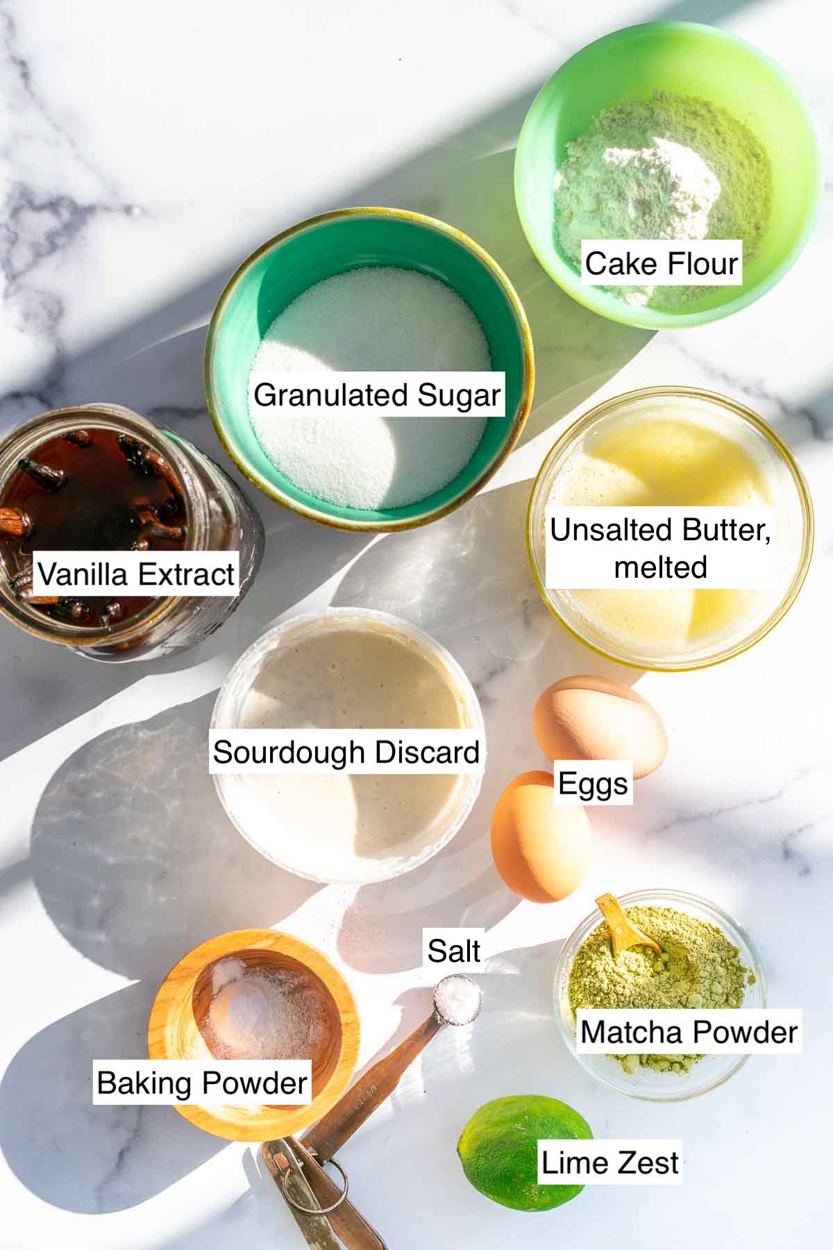 Ingredients needed for sourdough matcha madeleines including cake flour, sugar, salt, baking powder, butter, vanilla extract, eggs, matcha powder, and sourdough discard