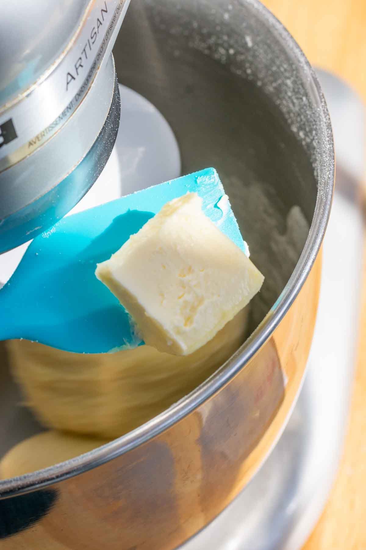 Spatula with a pat of butter over stand mixer bowl