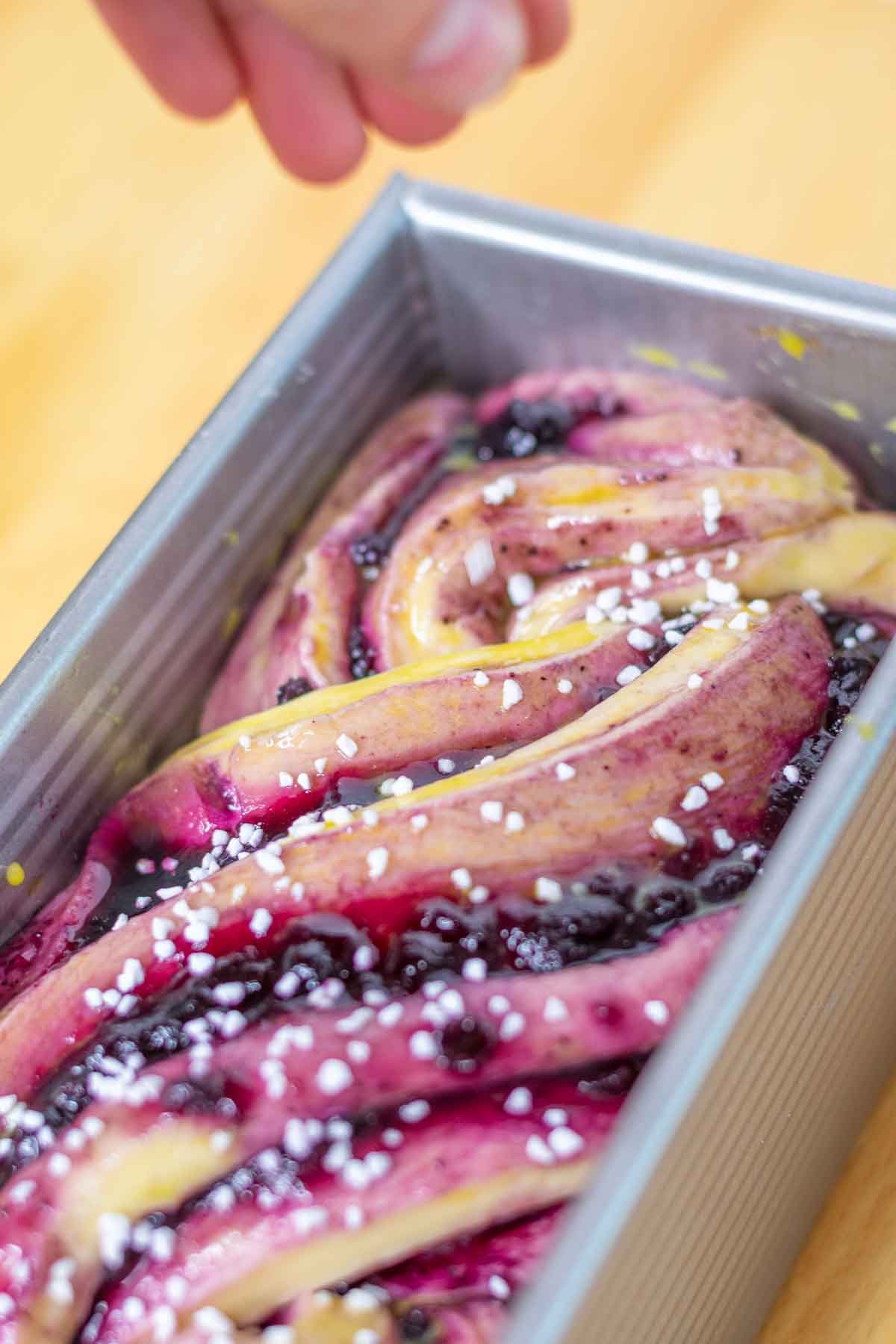 Sprinkling pearl sugar on top of proofed babka