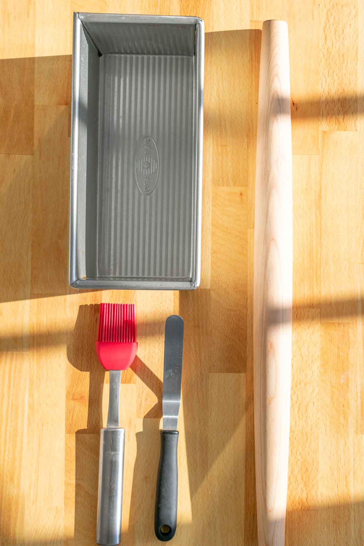 Tools needed for Sourdough babka including a bread loaf pan, pastry brush, offset spatula, and rolling pin