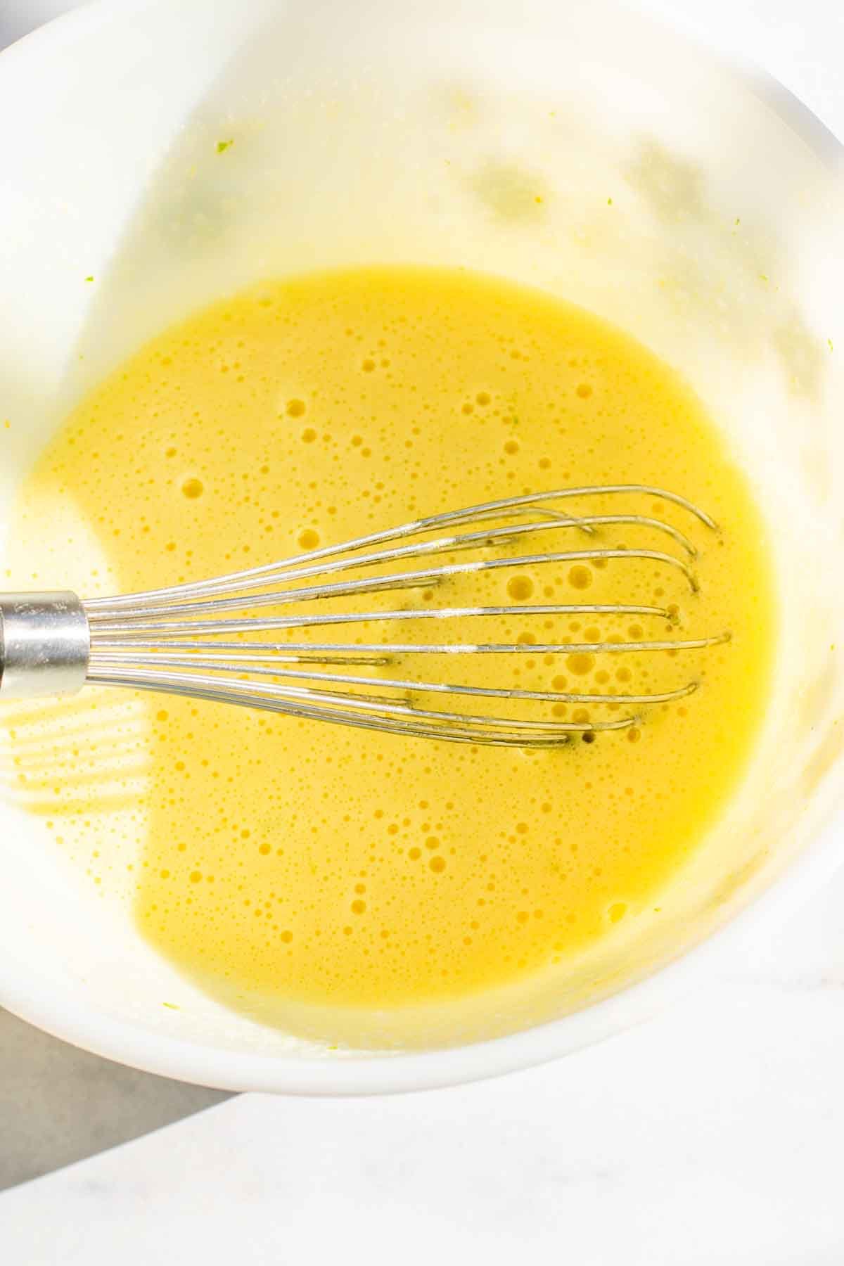 Whisked egg, sugar, and lime zest in a bowl