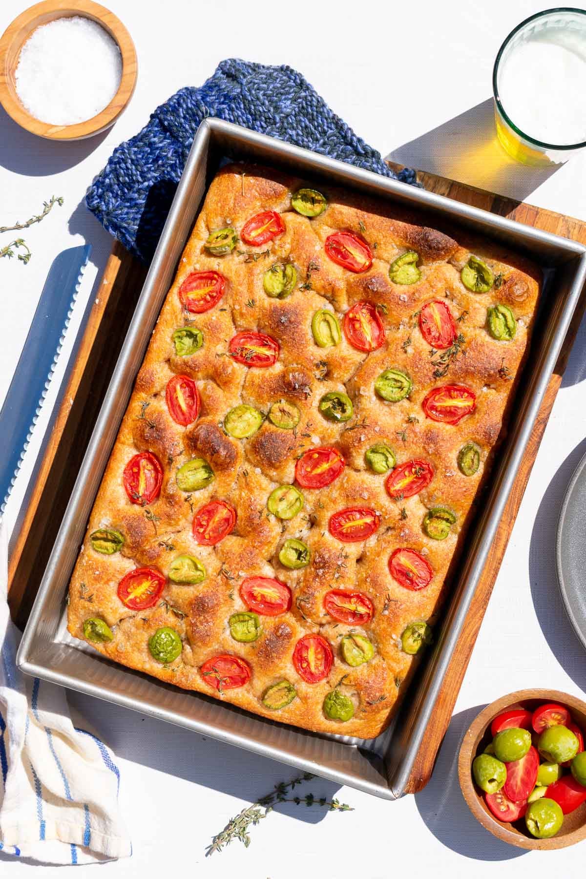Baked spelt sourdough focaccia in baking pan with tomatoes and olives