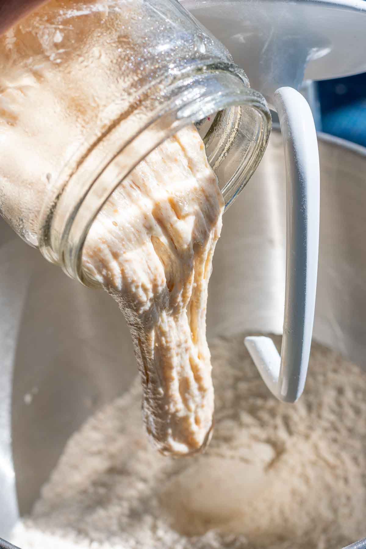 Pouring levain into bowl of dough