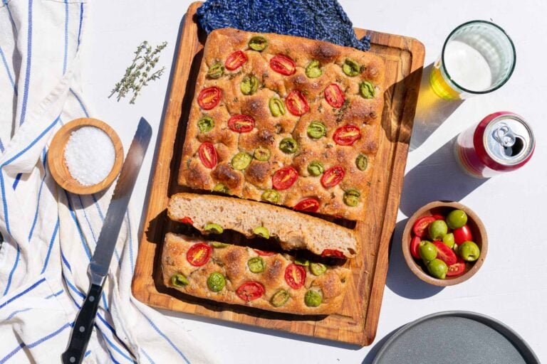 Spelt sourdough focaccia with olives and tomatoes on a cutting board
