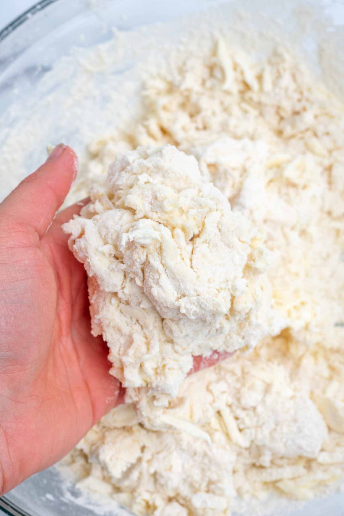 Hand holding a clump of sourdough shortcake dough