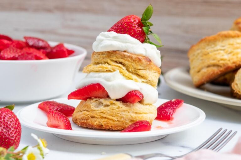 A sourdough strawberry shortcake with a flaky sourdough biscuit, whipped cream, and fresh strawberries on a plate