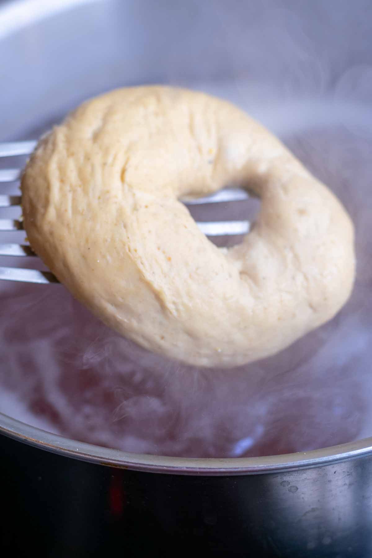 Dropping bagel into pot of boiling water