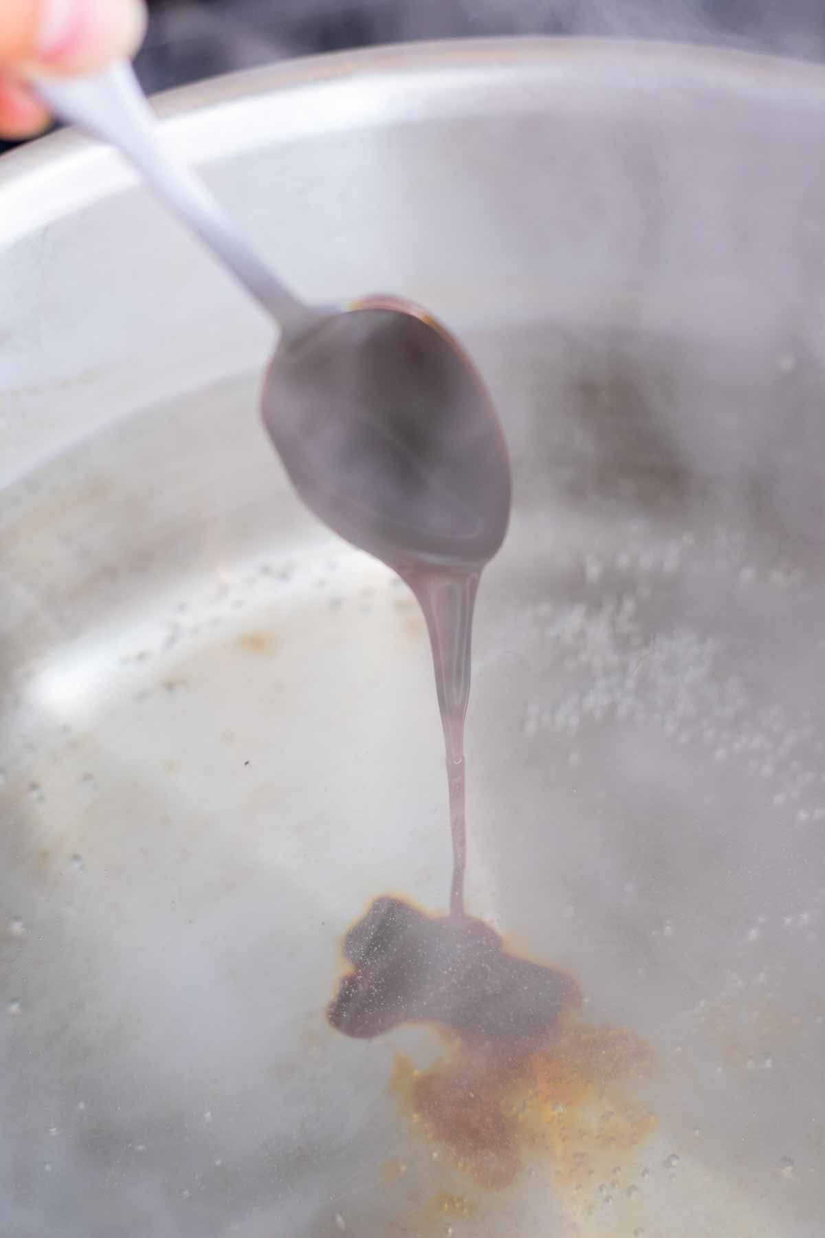 Adding barley malt syrup in spoon to a pot of boiling water