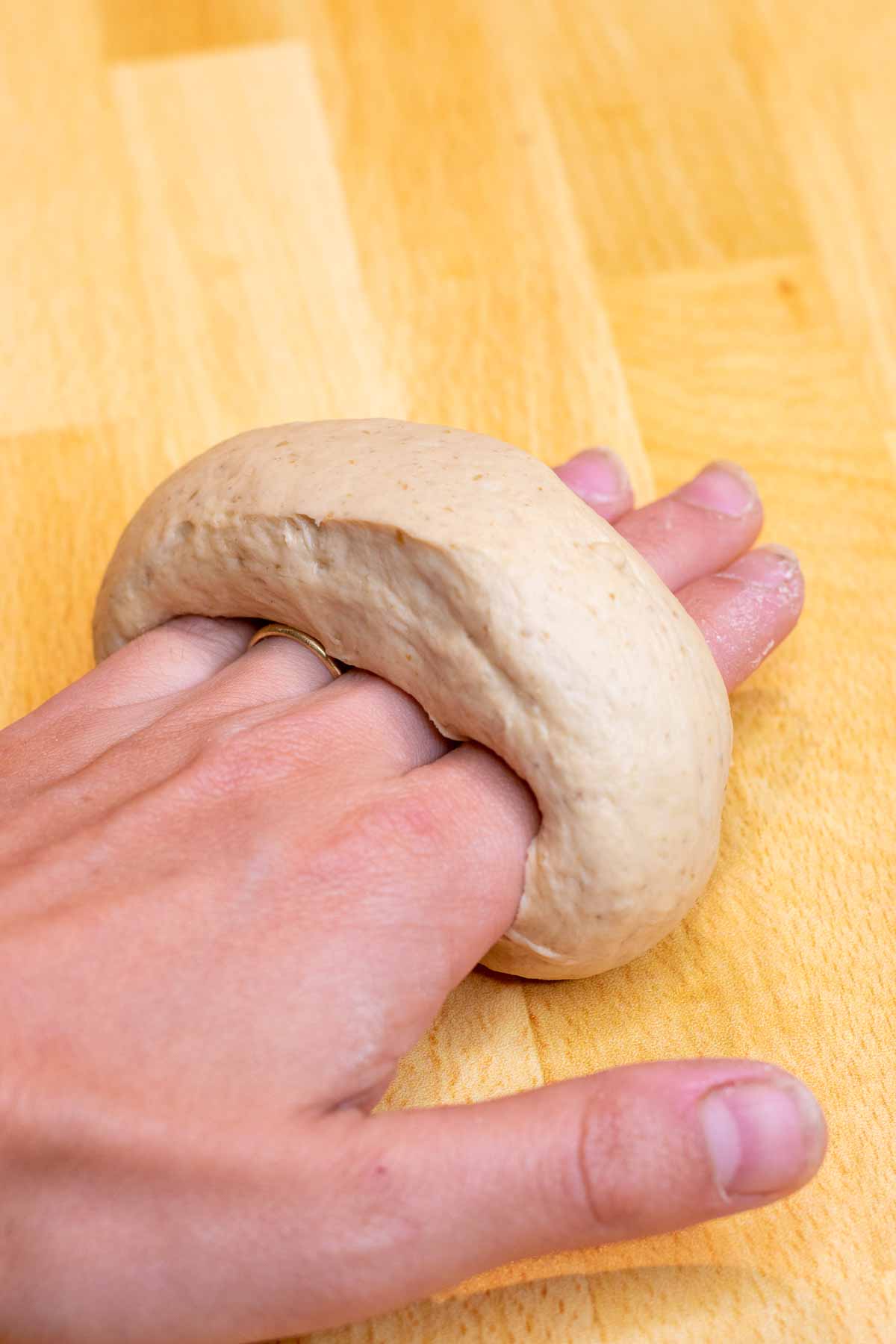 Hand shaping sourdough bagels on work surface