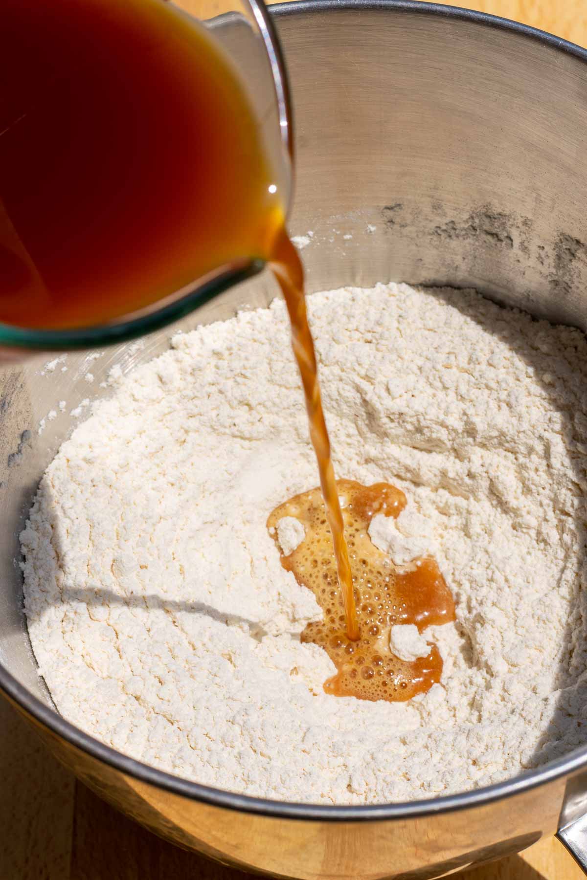 Pouring water and barley malt syrup into bowl of flour